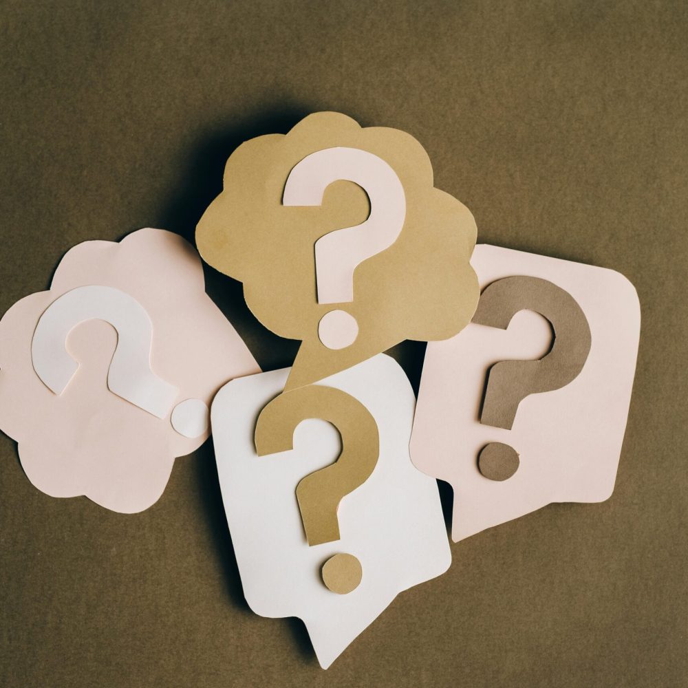 pexels-photo-5428836-5428836 Four paper cutouts of question marks in beige and white on a brown surface, symbolizing inquiry and curiosity.